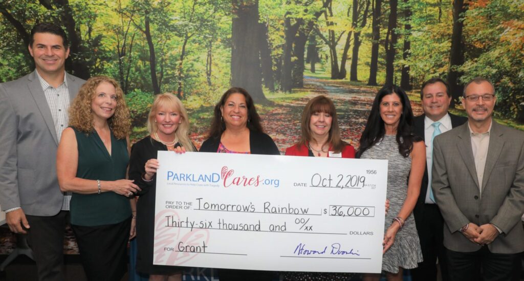 Six supporters hold an oversized Parkland Cares check for $20,000 made out to Tomorrow’s Rainbow, dated 11 December 2024.