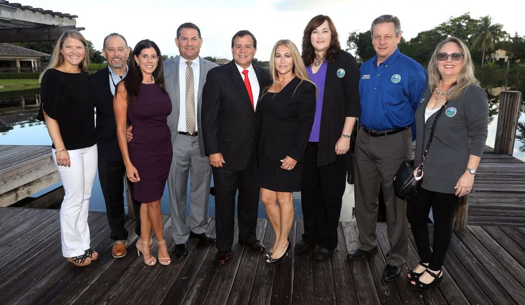 Nine Parkland Cares supporters and local officials stand together on a lakeside dock at an evening reception.
